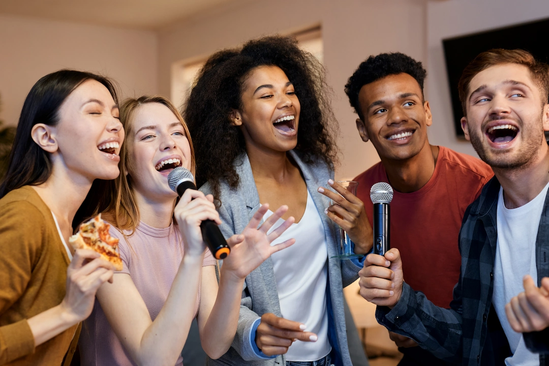 Photo d'un groupe de 5 collègues qui chantent tous dans des micros.